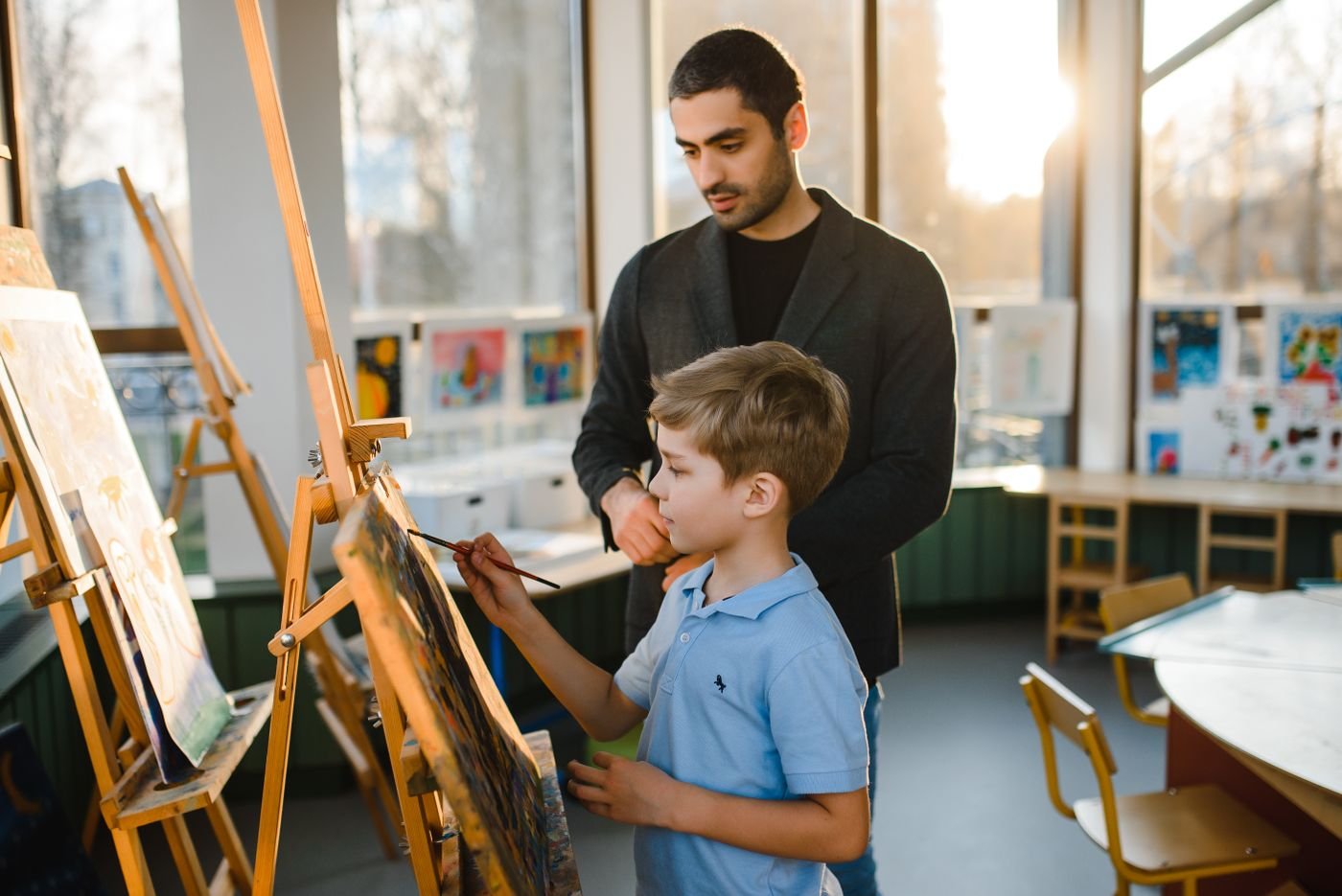 Teacher supporting a child at an easel